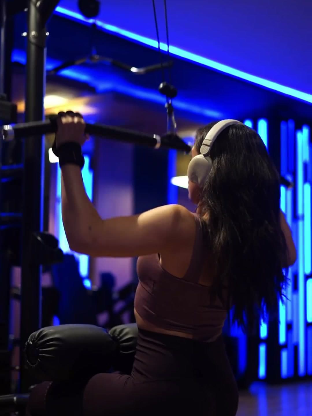 Membre à l'entraînement sous les panneaux néon bleus d'Elide Fitness Club